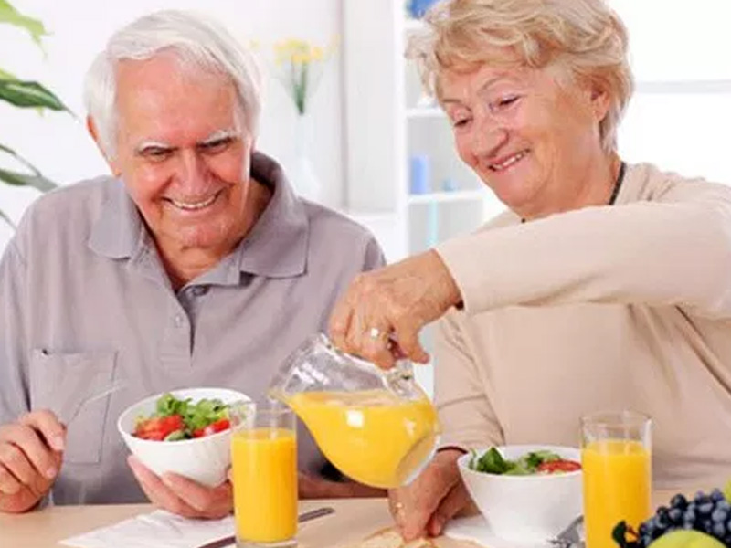 casal de idoso na mesa, tomando suco de laranja e comendo morango